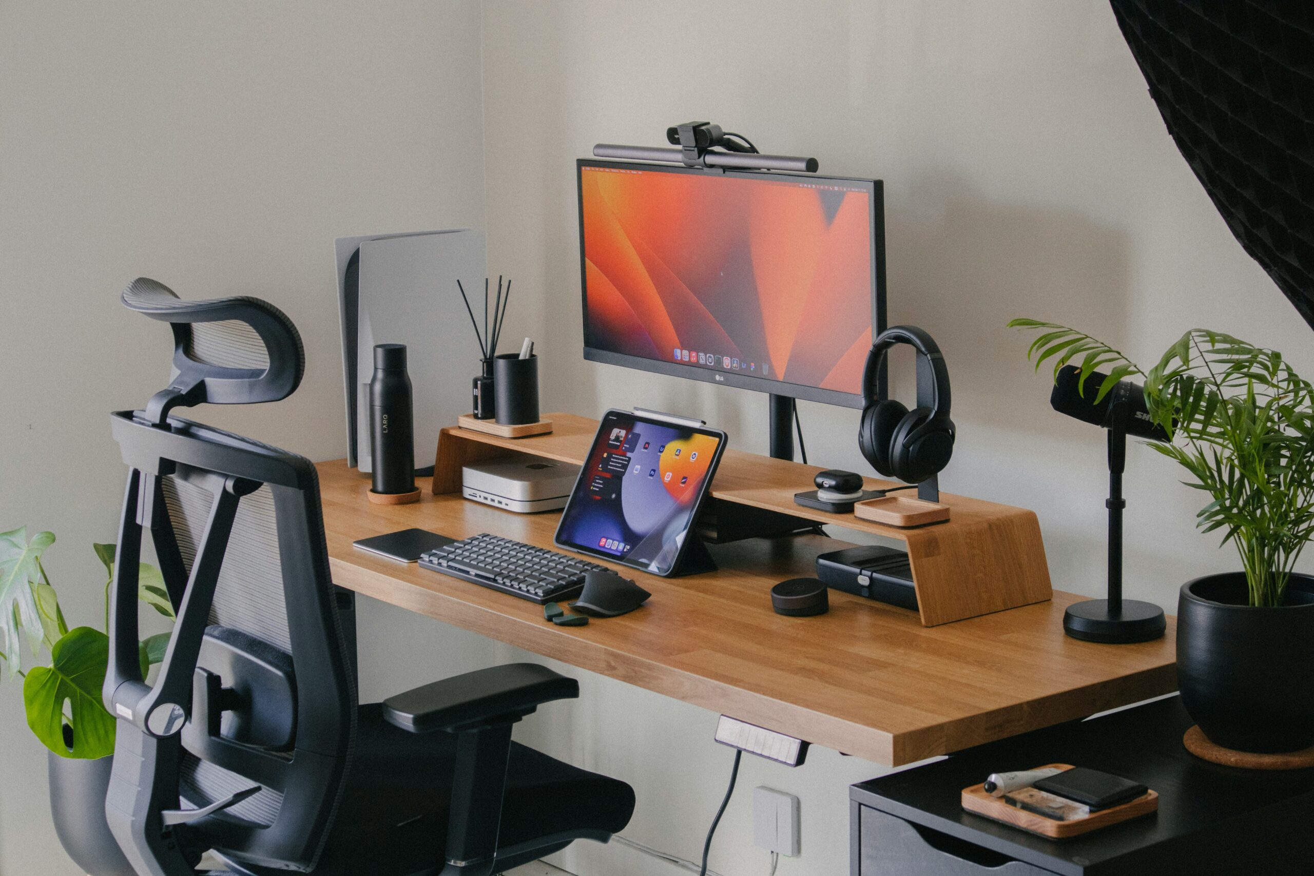 Minimalist productivity desk setup with monitor, keyboard, tablet and headphones